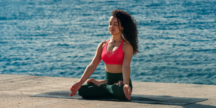Meditación Keishla meditando sobre cemento y mar de fondo